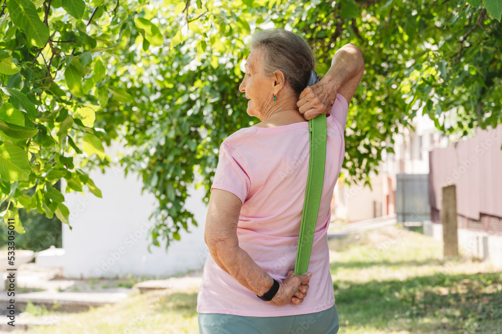 Senior woman exercising with resistance band standing amidst trees Senior woman exercising with resistance band standing amidst trees
