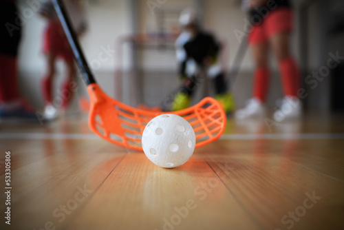 Close-up of floorball stick and ball during woman floorball match in gym. photo