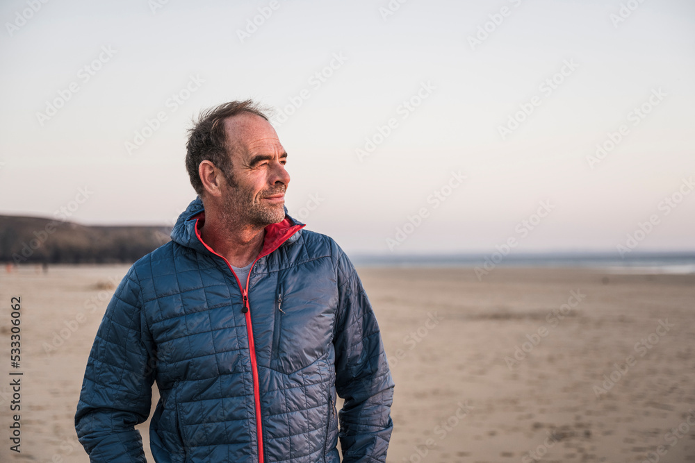 Contemplative mature man wearing jacket at beach Contemplative mature man wearing jacket at beach