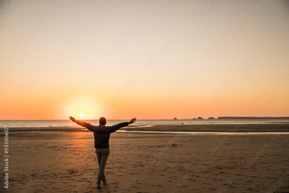 Man with arms outstretched enjoying on shore at sunset Man with arms outstretched enjoying on shore at sunset