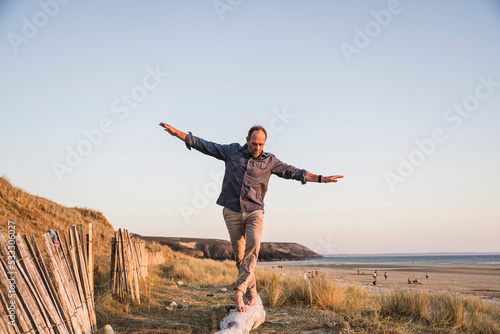 Mature man with arms outstretched walking on log