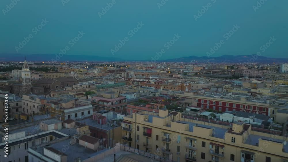 Forwards fly above buildings in evening city. Multistorey apartment houses with rooftop terraces in urban borough at dusk. Rome, Italy Forwards fly above buildings in evening city. Multistorey apartment houses with rooftop terraces in urban borough at dusk. Rome, Italy