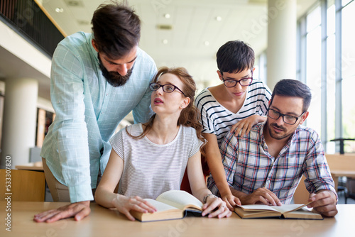 Happy university students studying with books in library. Group of multiracial people in college