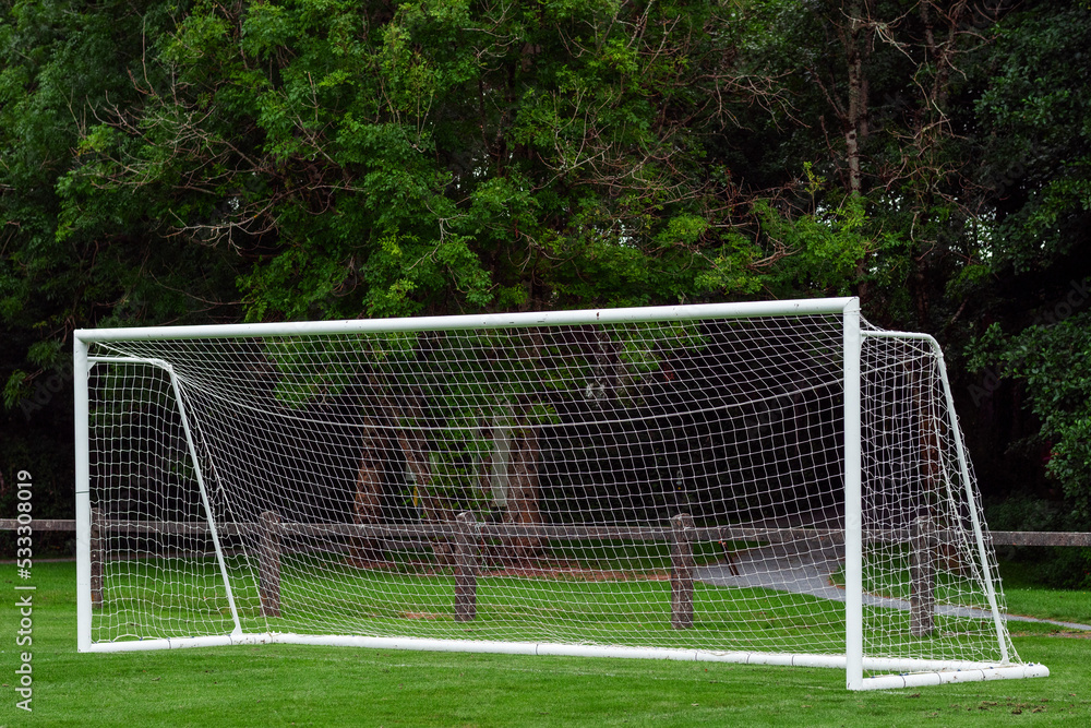 Fototapeta premium Side of football of soccer goal post with net in focus. Field out of focus. Sport background and equipment.
