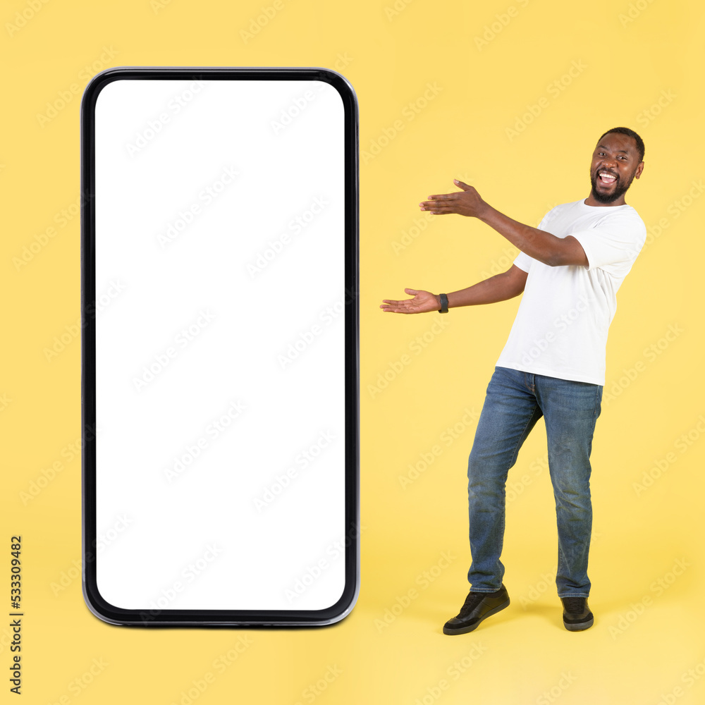 Joyful Black Guy Showing Large Phone Screen Over Yellow Background Joyful Black Guy Showing Large Phone Screen Over Yellow Background