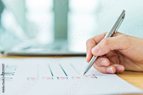 Hand with pen planning To Do List in office