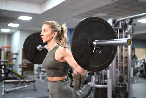 Caucasian woman training with barbells at the gym