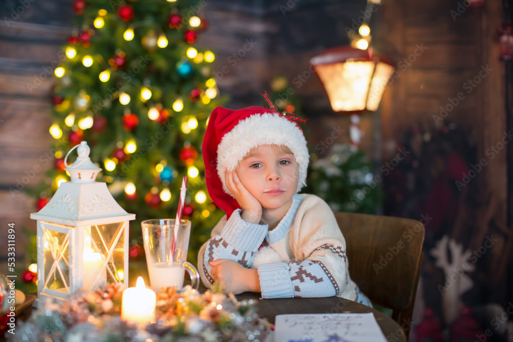 Cute toddler child, boy in a Christmas outfit, playing in a wooden cabin on Christmas, decoration around him Cute toddler child, boy in a Christmas outfit, playing in a wooden cabin on Christmas, decoration around him