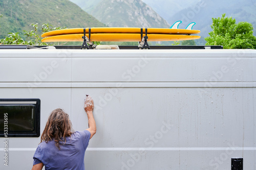 Man cleaning white van in nature