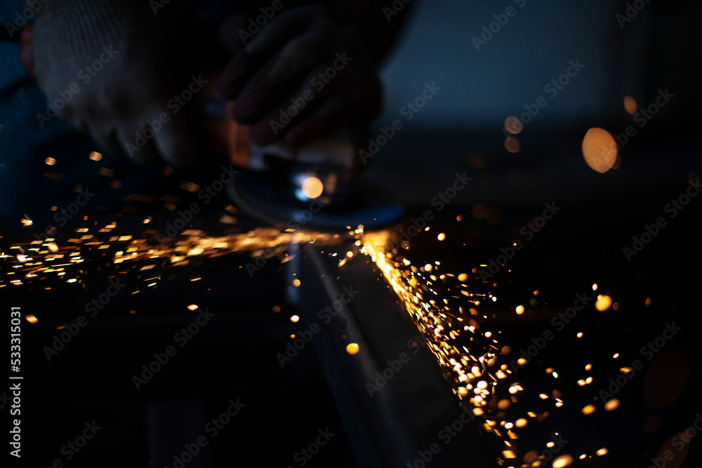 Sparks in dark. Metal grinding. Orange lights fly in different directions. Work in metal workshop.