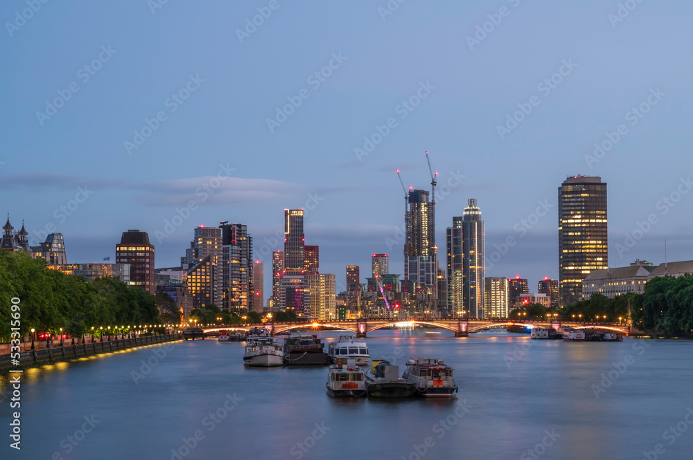 Fototapeta premium A view along the river Thames, to the skyscrapers of Vauxhall and Battersea, at night. The building are lit up