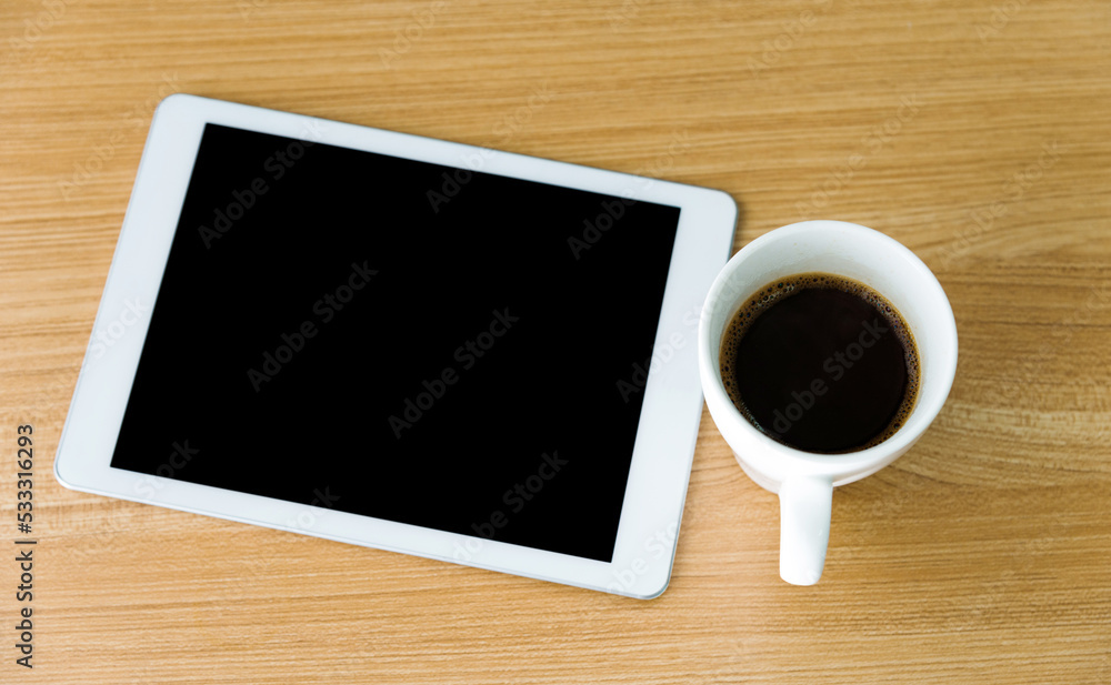 Digital tablet and a cup of coffee on wooden table Digital tablet and a cup of coffee on wooden table