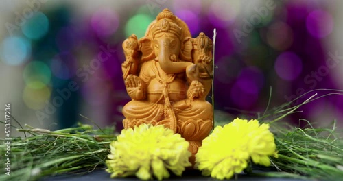 Close up shot of Hindu God Ganesh in a traditional Puja ceremony - Indian Hindu festival. Yellow flowers offered. photo