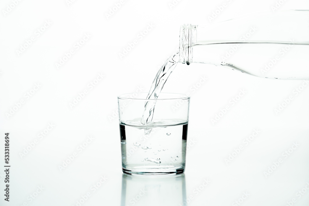 Glass bottle pouring water in a glass over a white background Glass bottle pouring water in a glass over a white background