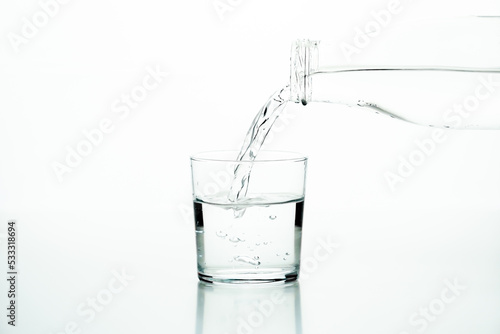 Glass bottle pouring water in a glass over a white background