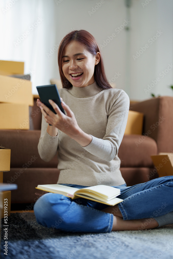 A portrait of a small startup, an SME owner, an Asian female entrepreneur checking orders to arrange the produce before packing the products in the inner boxes with the customers. Freelance concepts A portrait of a small startup, an SME owner, an Asian female entrepreneur checking orders to arrange the produce before packing the products in the inner boxes with the customers. Freelance concepts