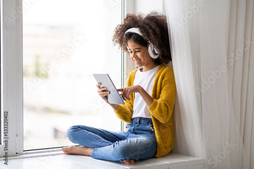 Cheerful african american girl using digital tablet and headset