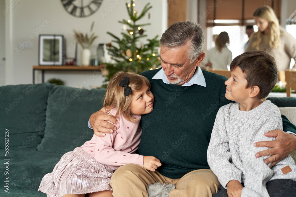 Grandfather and grandchildren bonding on sofa at Christmas time
