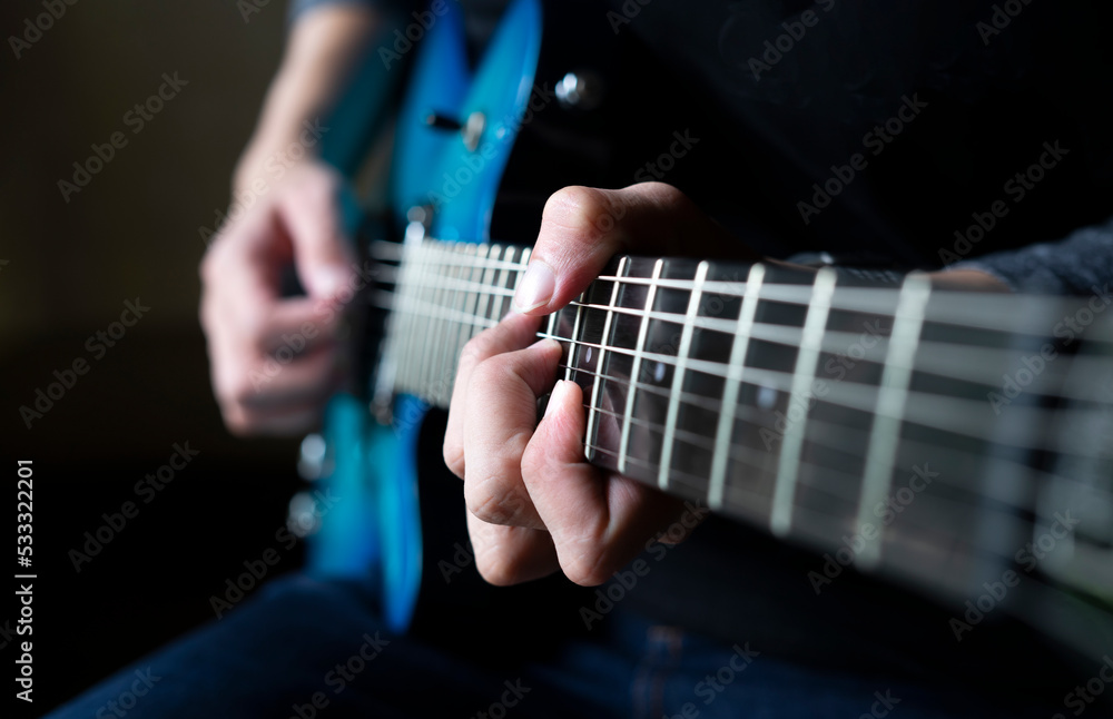 guitarist man playing guitar, a man sitting and practicing electric guitar on dark background