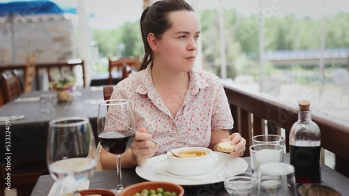 Portrait of woman spending time on open terrace of restaurant and eating traditional spanish gazpacho. High quality 4k footage