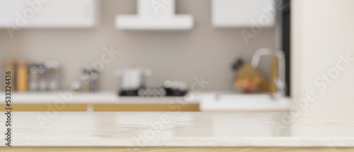 White marble tabletop with empty space over blurred modern home kitchen in the background