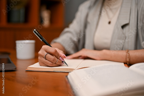 Smart Asian businesswoman writing something on her notebook during working in her office.