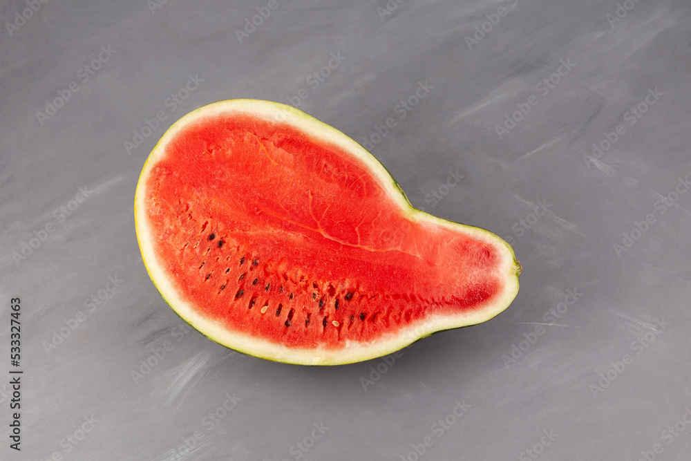 Half of pear-shaped watermelon. Deformed ugly watermelon. Concept - Food waste reduction. Eating imperfect foods Half of pear-shaped watermelon. Deformed ugly watermelon. Concept - Food waste reduction. Eating imperfect foods