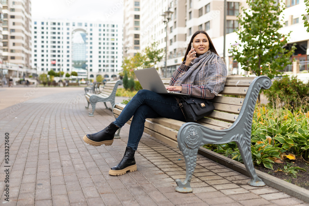 young woman working on a laptop online in the park on a bench, freelance work concept