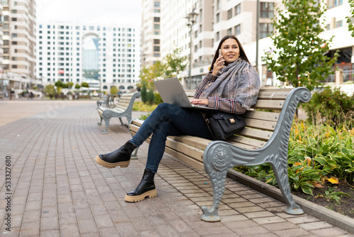 Cuadro en lienzo young woman working on a laptop online in the park on a bench, freelance work co