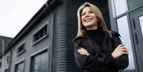 portrait of a mature woman head with a wide smile on her face in business clothes against the backdrop of the facade of a business center, concept of a strong successful woman