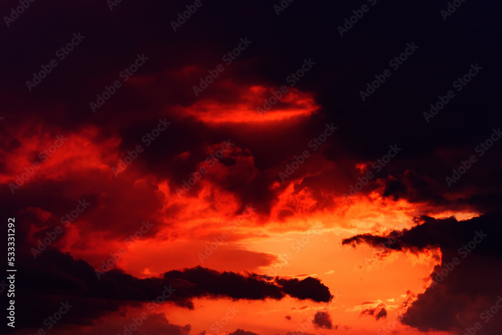 Dark orange sunset sky with heavy stormy clouds in summer