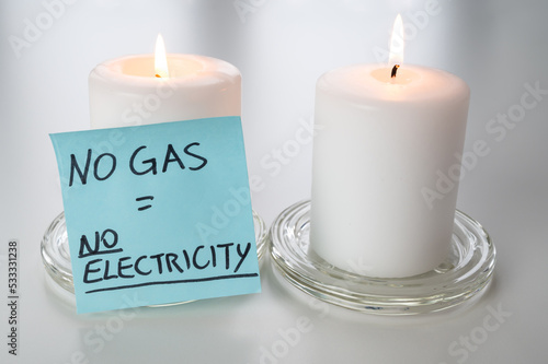 Lighted candles, with blue ticket and text "no gas, no electricity". Rationing, shortage of electricity and gas, rising tariffs. 