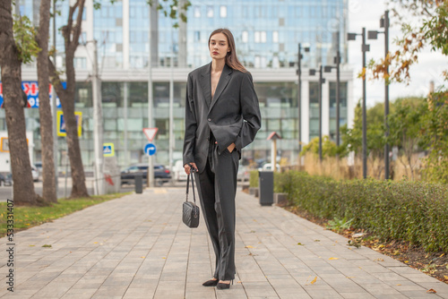 Young sexy woman in male business suit posing on the street