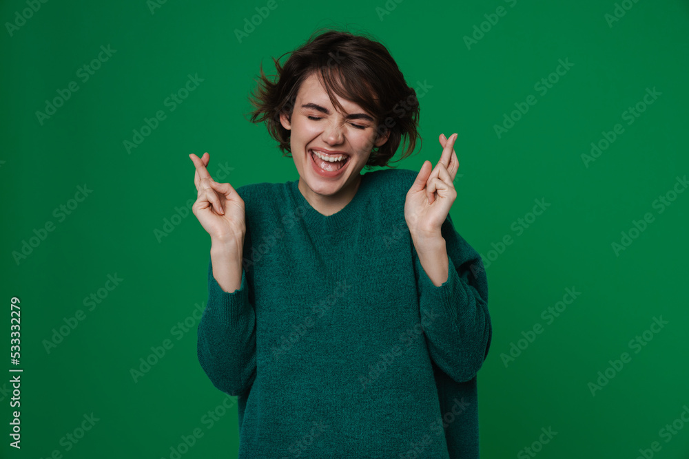 Young woman smiling while posing with fingers crossed for good luck Young woman smiling while posing with fingers crossed for good luck