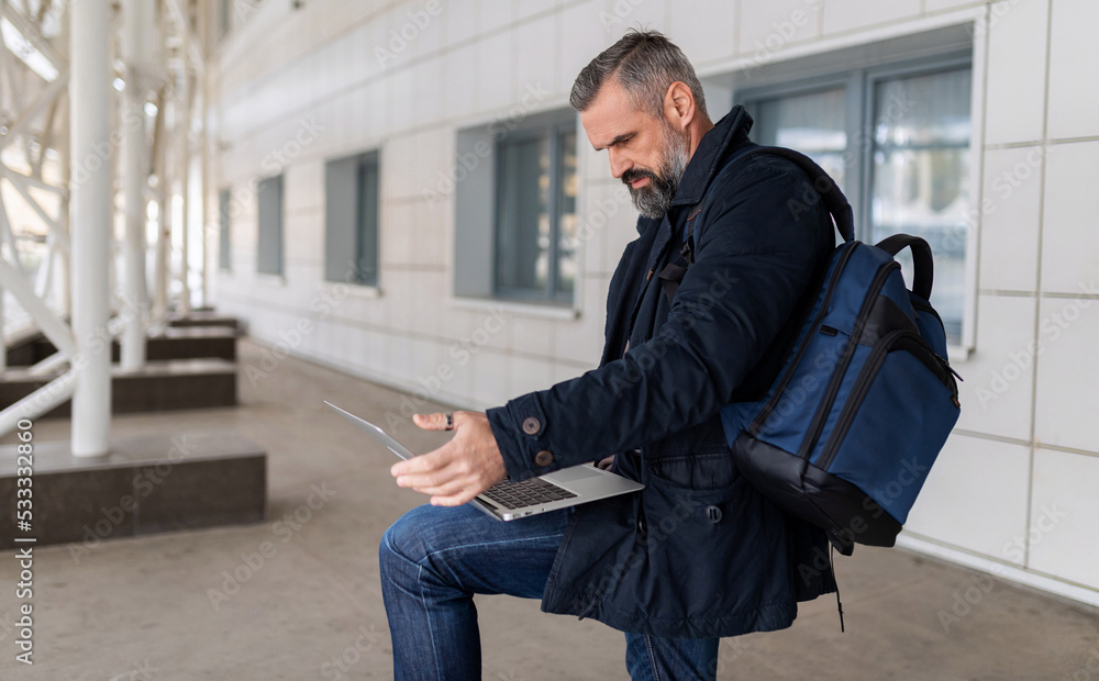 mature male entrepreneur working on laptop online in airport lounge, freelance work concept mature male entrepreneur working on laptop online in airport lounge, freelance work concept