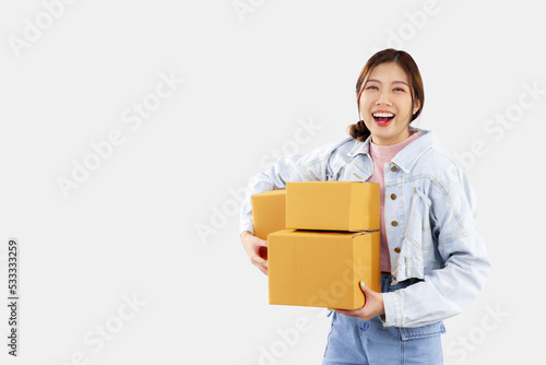 Online shopping delivery concept. Young asian girl holding and carrying brown boxes for shipping to the client. Online marketing and delivery. © CREATIVE WONDER