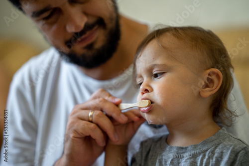 Dad helps his young son brush his teeth. The father takes care of the child.