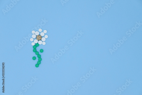 Medical pills in the shape of a flower on blue background with copy space. Medical flat lay. world pharmacists day