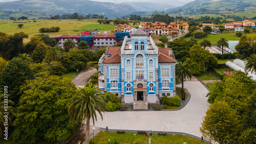 Aerial drone shot flying over the blue Museum of Emigration in the city of Colombres. photo