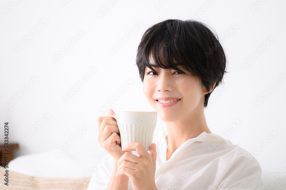 部屋でくつろいでコーヒーなどの飲み物を飲む女性　アップ