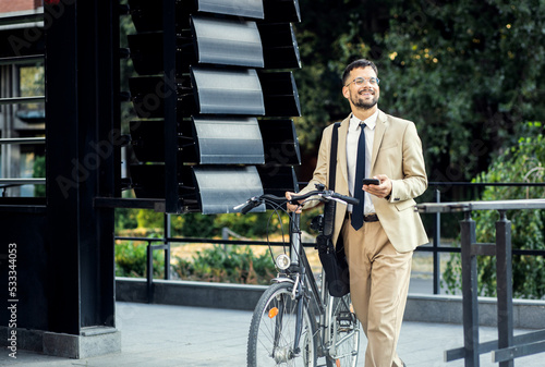 Portrait of business man with bicycle standing in front of office building.