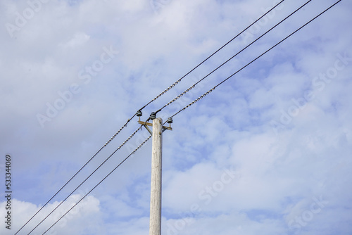 Looking up at power pylons with blue sky and clouds background