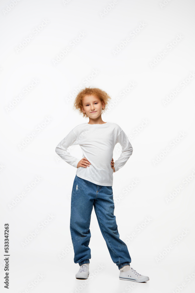 Full-length portrait of little girl, kid in white long sleeve blouse and jeans isolated over white background. Fashion, happy childhood Full-length portrait of little girl, kid in white long sleeve blouse and jeans isolated over white background. Fashion, happy childhood