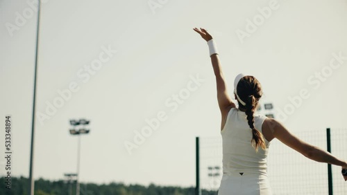 4k video female tennis player in white serving. Young woman hit the tennis ball with racket. Tennis serve on sky background.