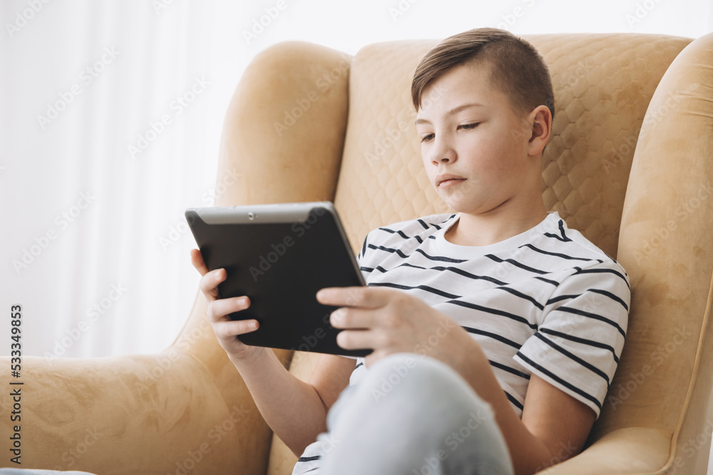 Teenage boy using tablet having video chat on internet online at home. Child watching movie, playing video game. Social media concept. Online education. Distance learning Teenage boy using tablet having video chat on internet online at home. Child watching movie, playing video game. Social media concept. Online education. Distance learning