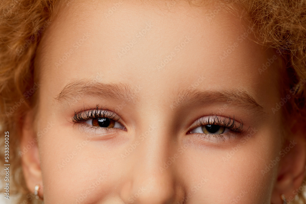 Closeup of little girl's eye with black curly eyelashes. Kids ophthalmology. Children female face with open eyes. Closeup of little girl's eye with black curly eyelashes. Kids ophthalmology. Children female face with open eyes.