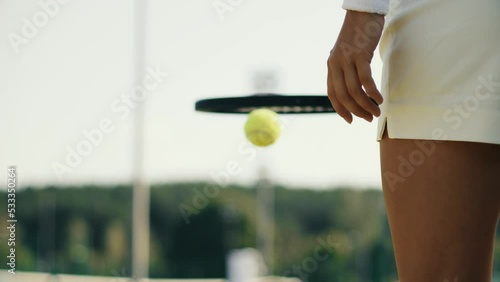 4k video Unrecognizable young woman in white on tennis grass court bouncing the ball before serving. Female playing tennis on sunny day. Tennis club concept.