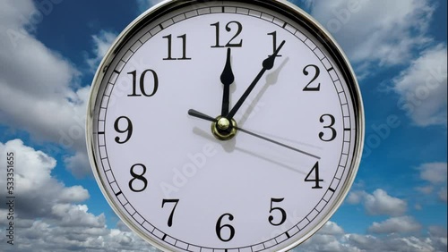 Time flies backwards into the past. Timelapse clockface going backwards back in time and zooms away from the camera with a timelapse sky and clouds in the background, photo