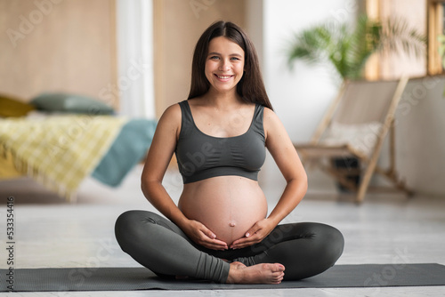 Healthy Pregnancy. Young Pregnant Woman Sitting Yoga Mat And Touching Belly