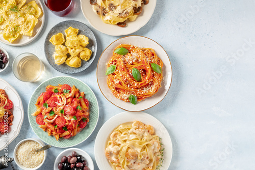 Italian pasta, various dishes, overhead flat lay shot with copy space. Spaghetti with tomato sauce, seafood pasta, penne with chicken etc, with wine